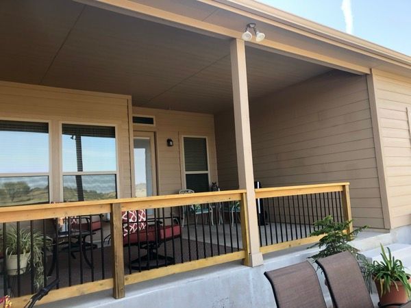 A porch with a wooden railing and a table and chairs on it