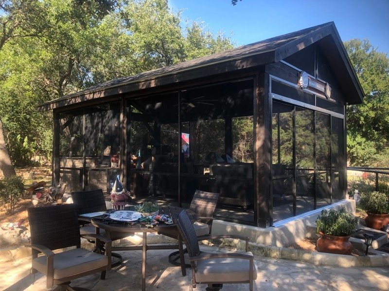 A screened in porch with a table and chairs in front of it.