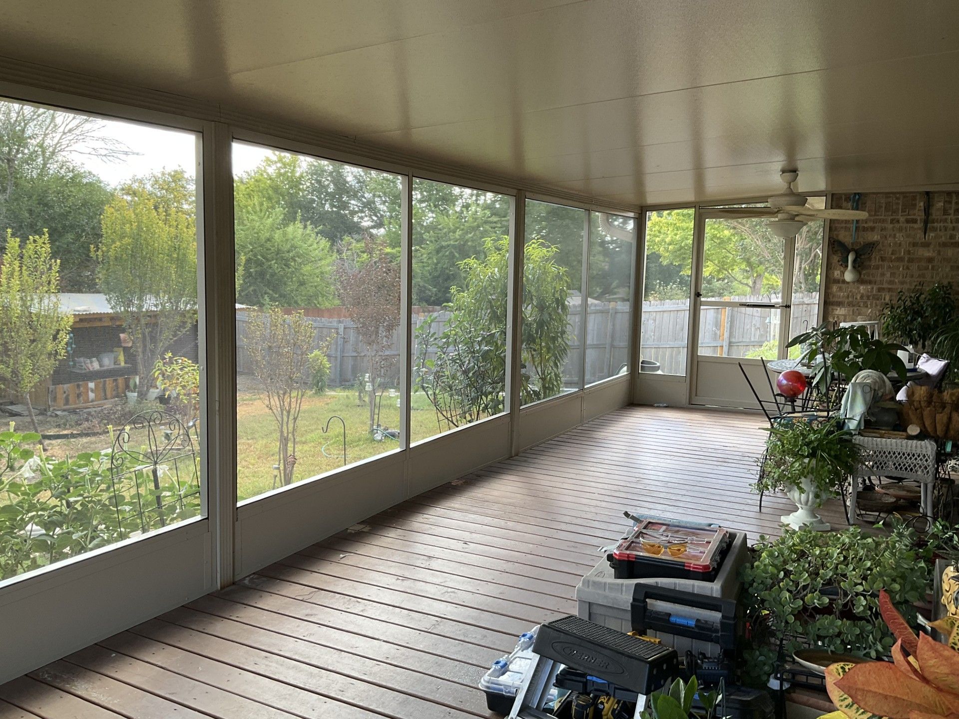 A screened in porch with a lot of windows and a ceiling fan.
