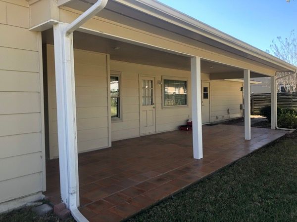 A white house with a covered porch and a gutter