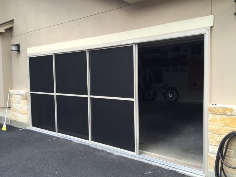 A sliding glass garage door with black screens on it