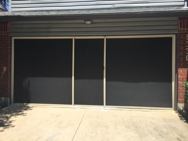 A garage door with a screen on it and a brick building in the background.