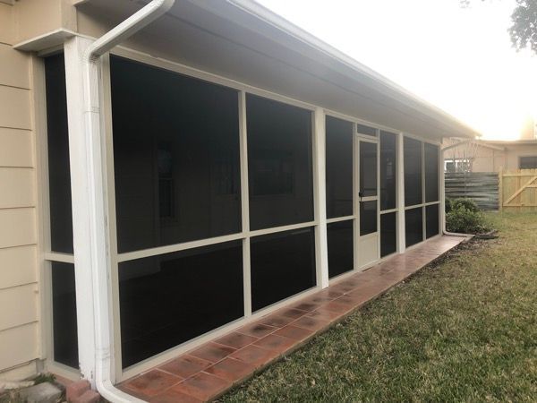 A screened in porch with black screens on the side of a house.