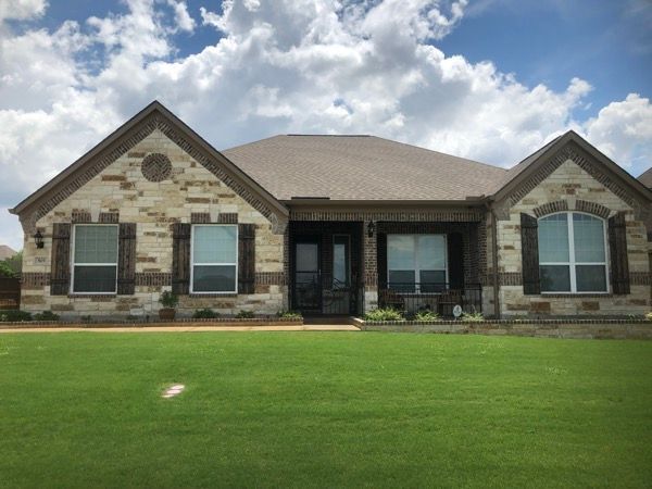A large brick house with a lush green lawn in front of it