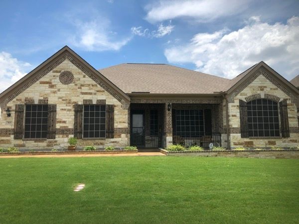 A large brick house with a large lawn in front of it