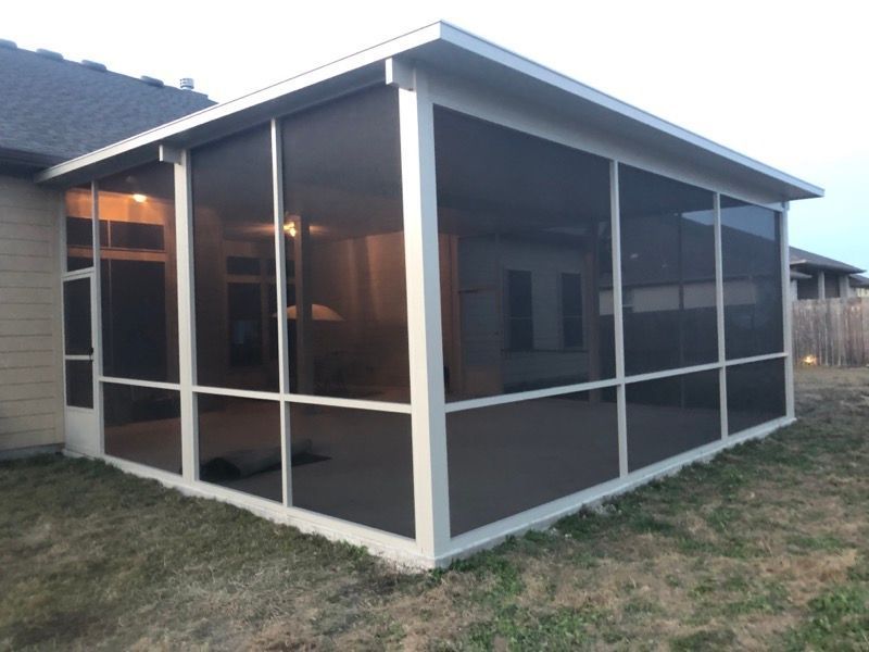 A screened in porch in the backyard of a house