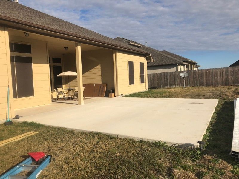 There is a concrete patio in the backyard of a house.
