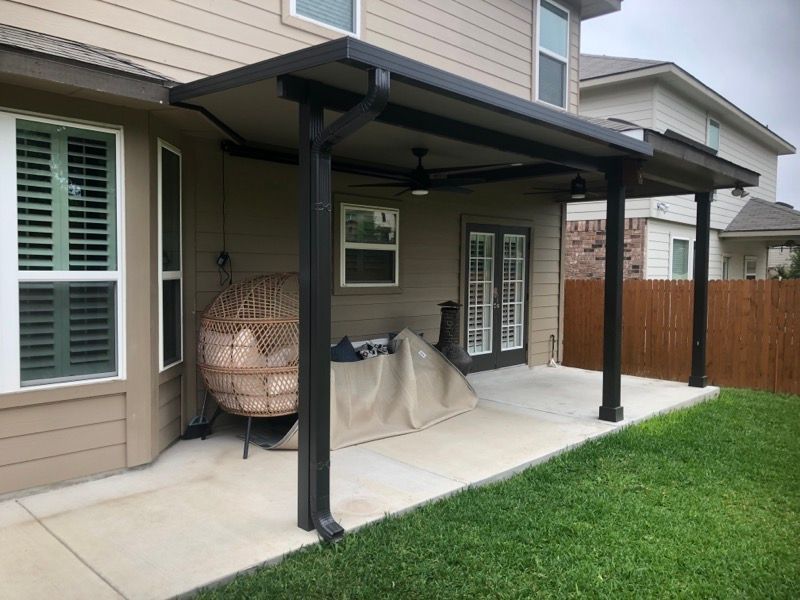 The backyard of a house with a covered patio and a chair.