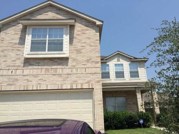 A purple car is parked in front of a brick house