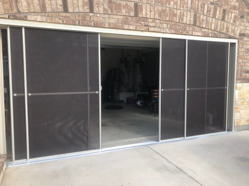 A sliding screen door is open to a garage.