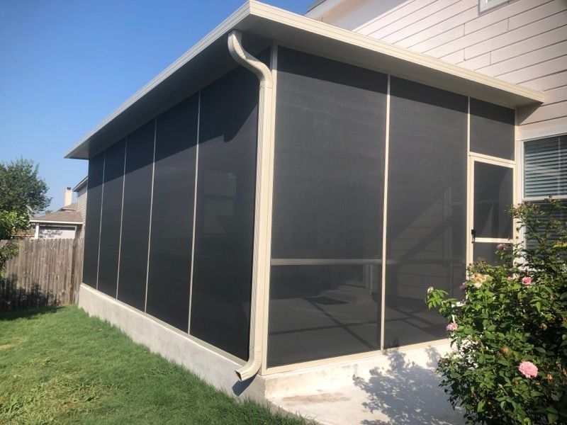 A screened in porch in the backyard of a house.