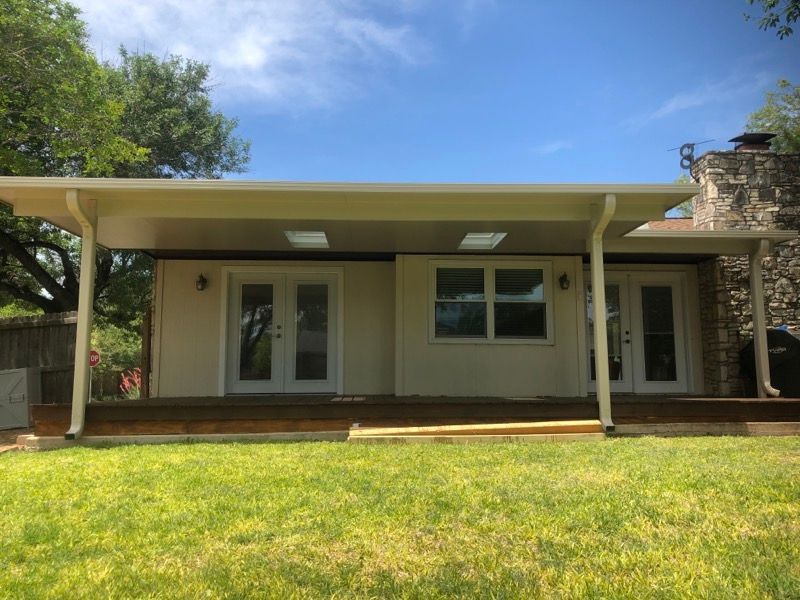 The back of a house with a covered porch and sliding glass doors.