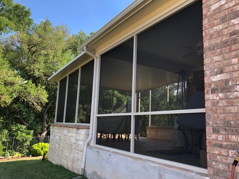 A screened in porch with a brick wall and a lot of windows.