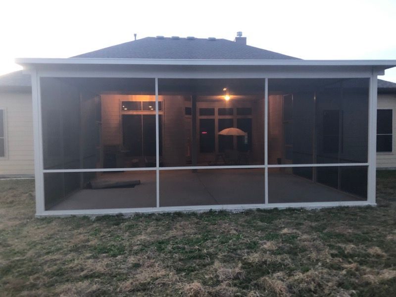 A screened in porch with a house in the background