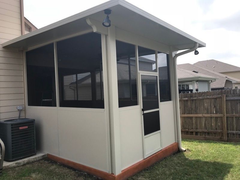 A screened in porch in the backyard of a house.