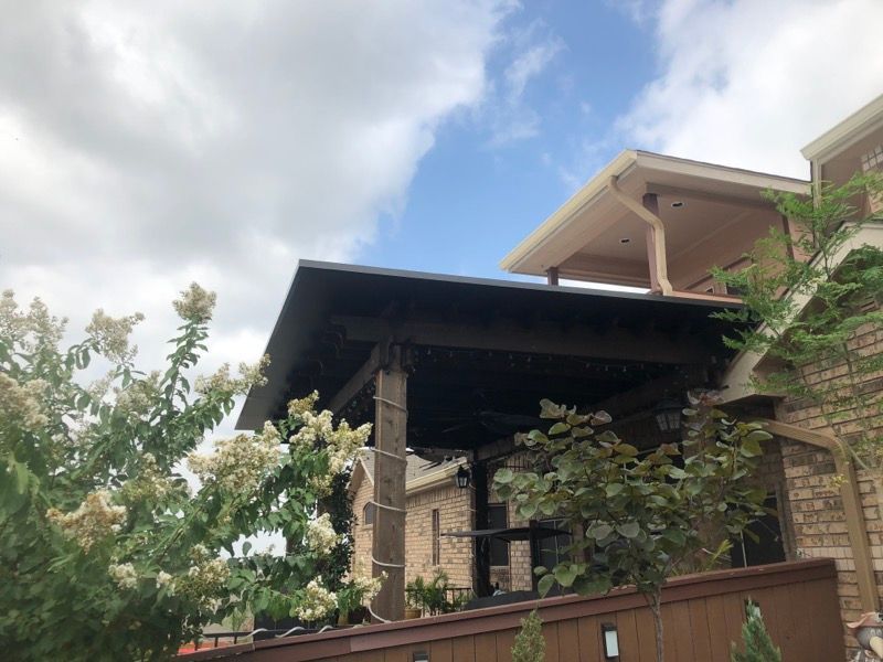 A house with a covered porch and a roof with a blue sky in the background.