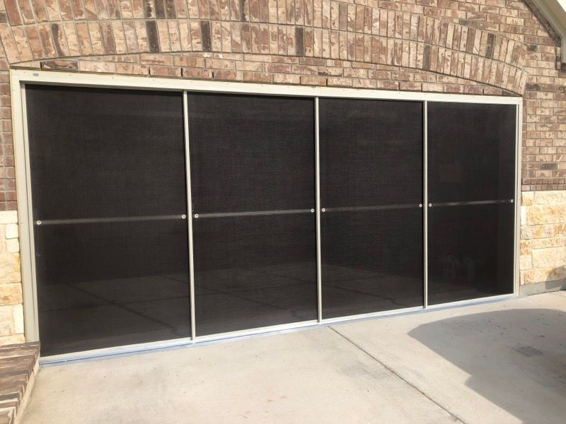 A brick house with a screened in garage door.