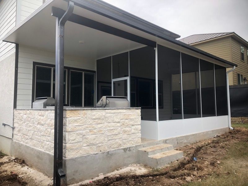 A screened in porch with a grill and a drainpipe on the side of a house.