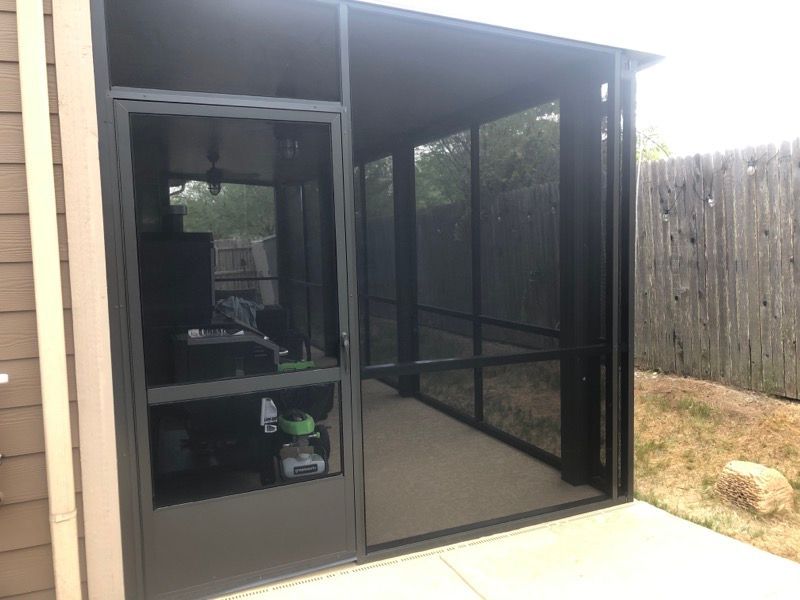 A screened in porch with a fence in the background.