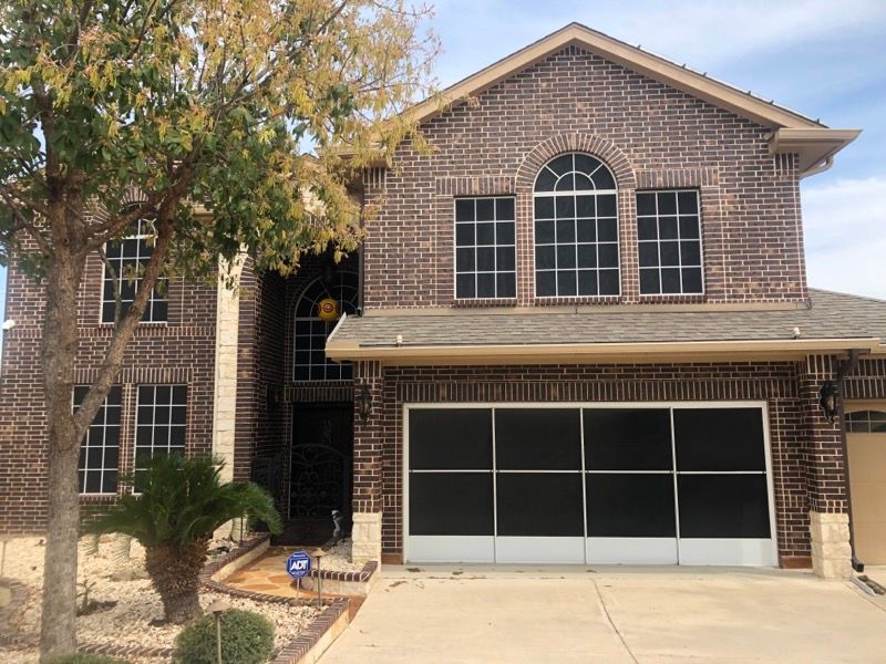 A large brick house with a screened in garage door.