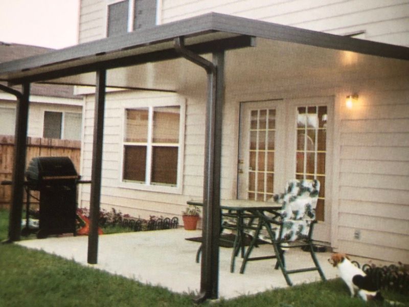 A white house with a covered patio with a table and chairs
