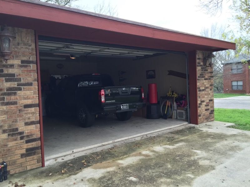 A truck is parked in a garage with the door open.