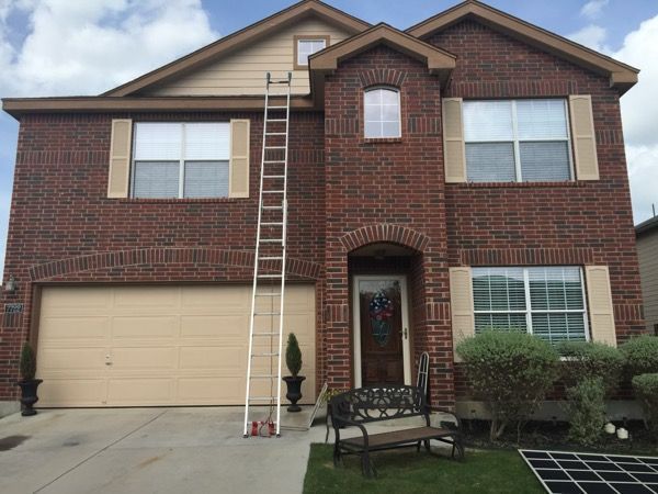 A large brick house with a ladder in front of it.