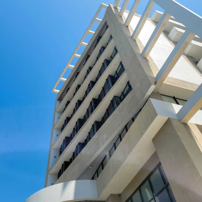 Modern white office building shot from below against a bright blue sky