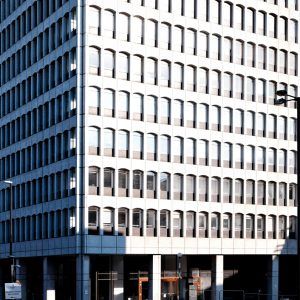 Modern office building with white patterned facade and dark ground floor storefronts