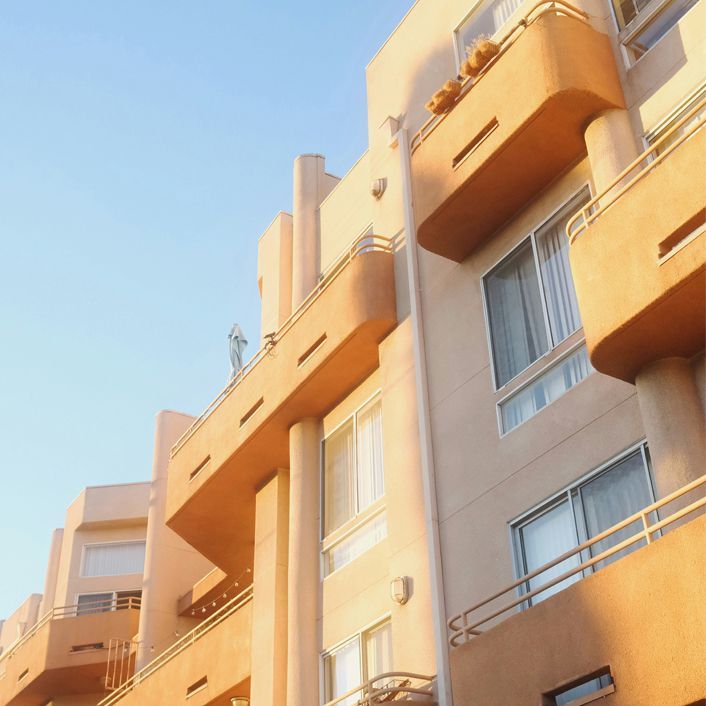 Orange apartment buildings against a clear blue sky, viewed from below