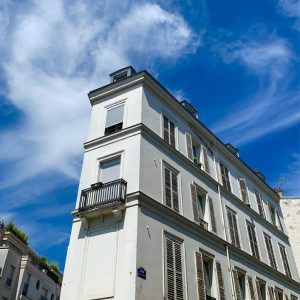 White multi-story corner building with balconies against a blue sky