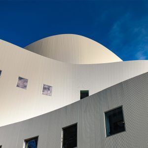 Curved white modern building against a bright blue sky