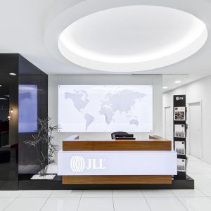 Modern office reception desk with JLL logo and a world map wall display in a bright lobby