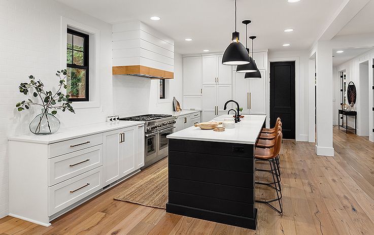 Bright modern kitchen with white cabinets, black island, and wood floors