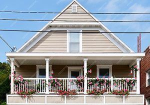 Front porch of a beige house with white trim and pink flowers in hanging baskets