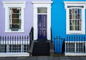Pastel townhouse facade with white trim, blue door and steps, and black iron railings