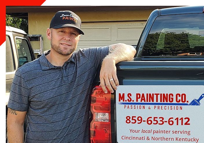 Man leaning on truck with M.S. Painting Co. sign, smiling outdoors