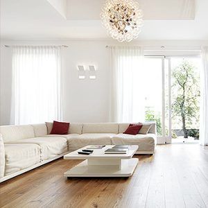 Bright modern living room with white sectional sofa, red pillows, low coffee table, and large windows.