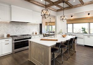Modern kitchen with white cabinets, large island, pendant lights, and dark wood floors