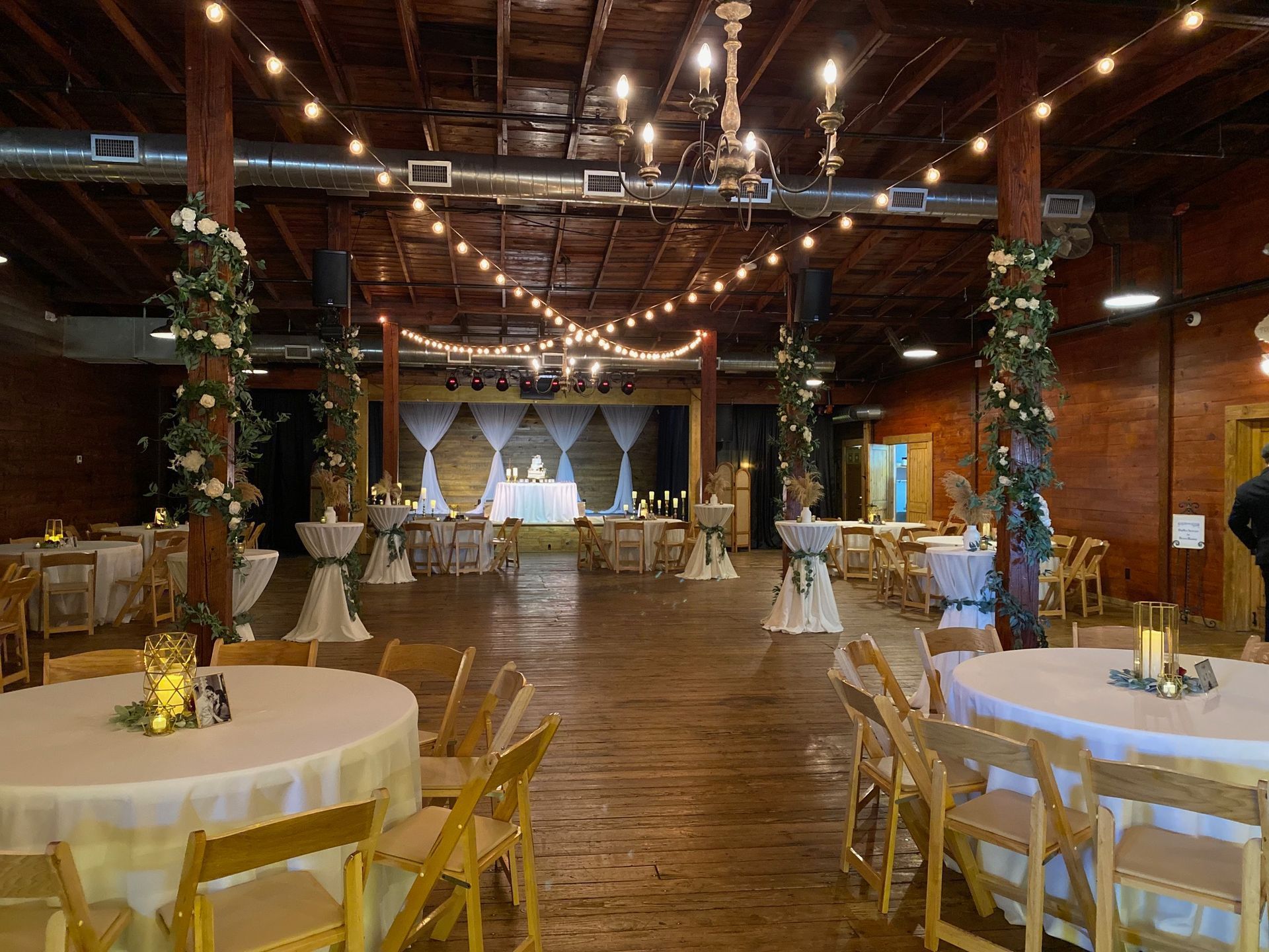 A large room with tables and chairs set up for a wedding reception.