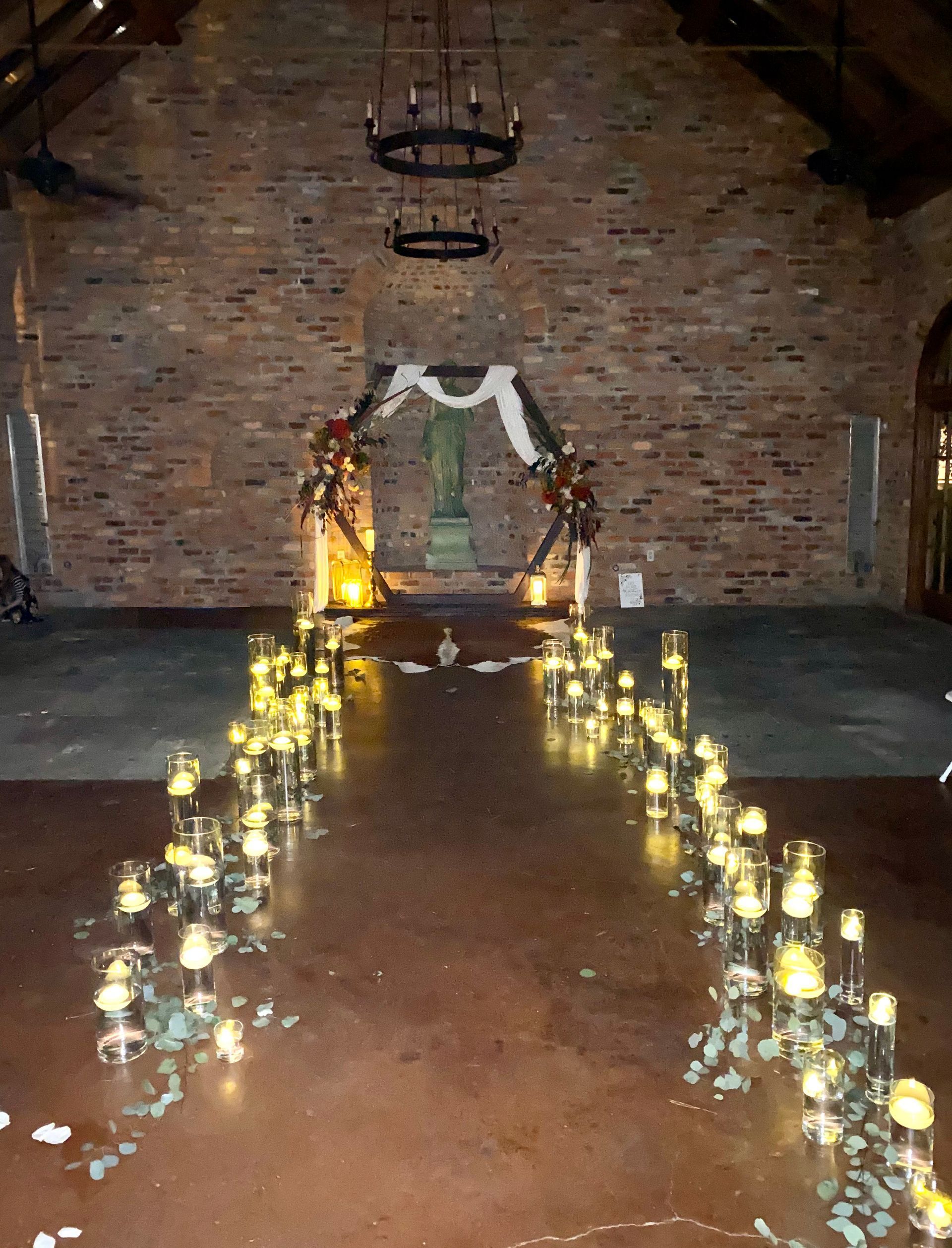 A candle lined aisle in a church with a brick wall in the background