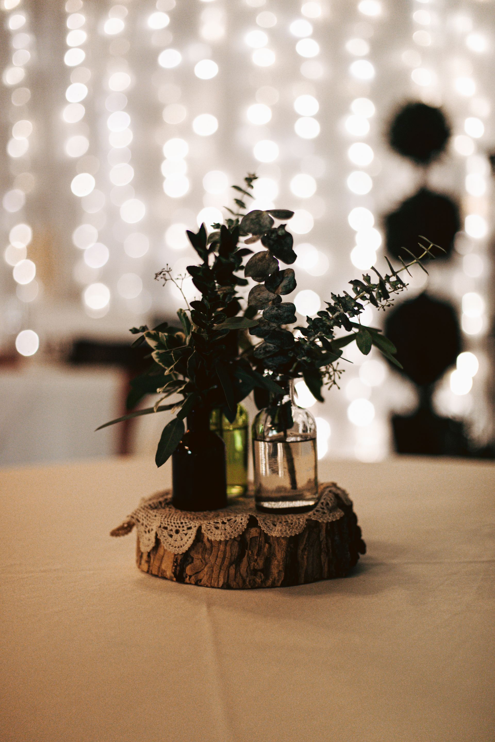 Two vases filled with flowers are sitting on a wooden stump on a table.