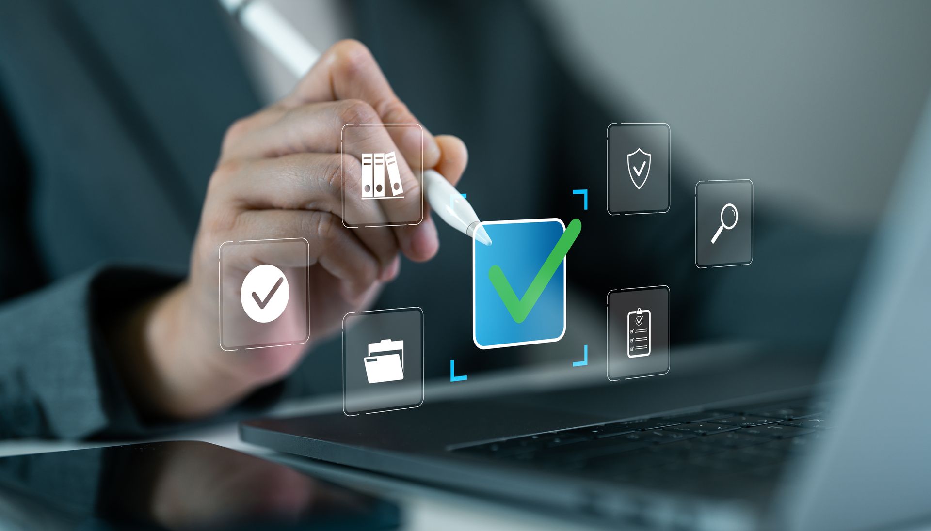 Person using stylus to select a digital checkmark on a laptop screen, representing approval or completion.