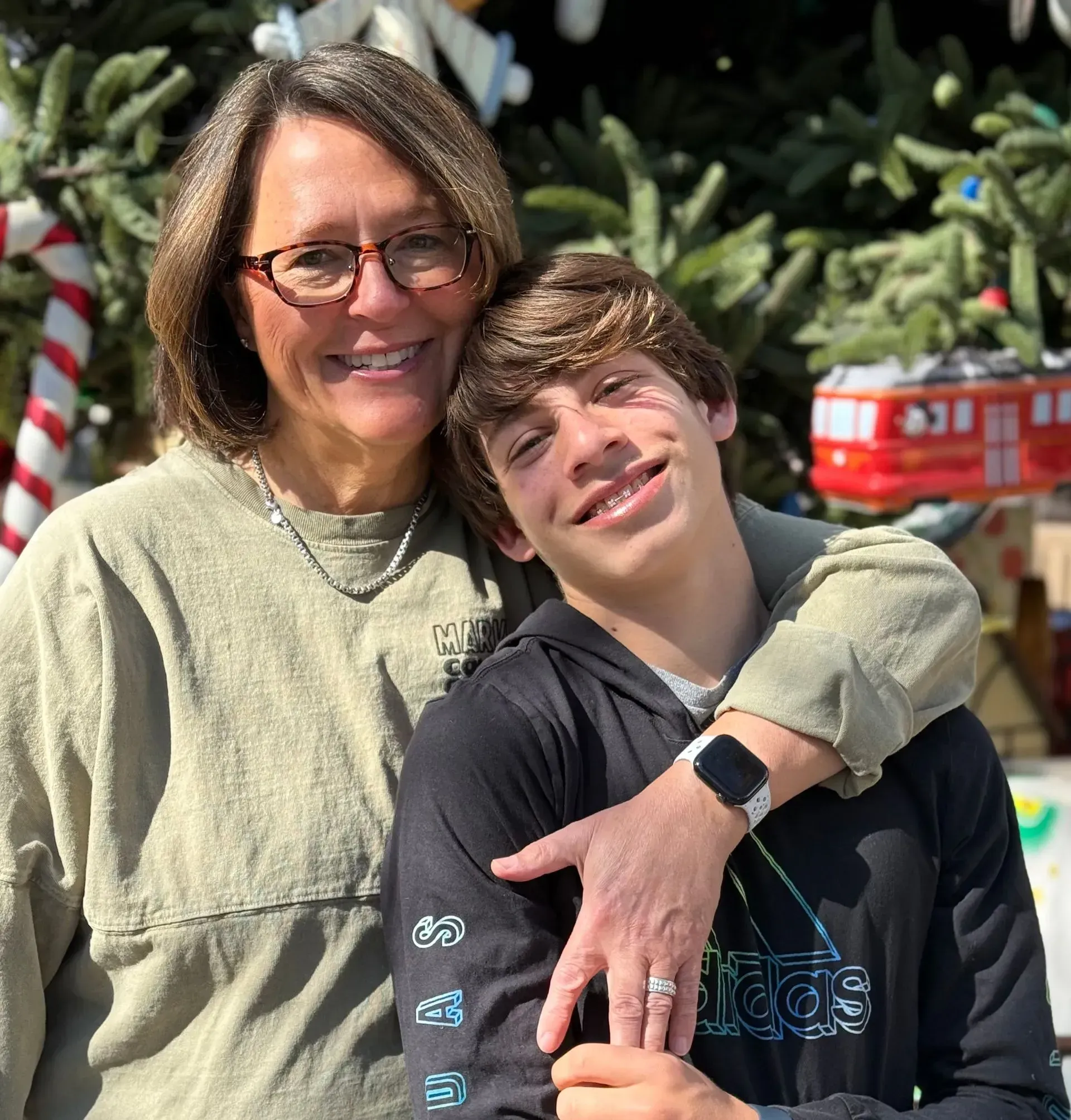 A woman and a boy are posing for a picture in front of a christmas tree.