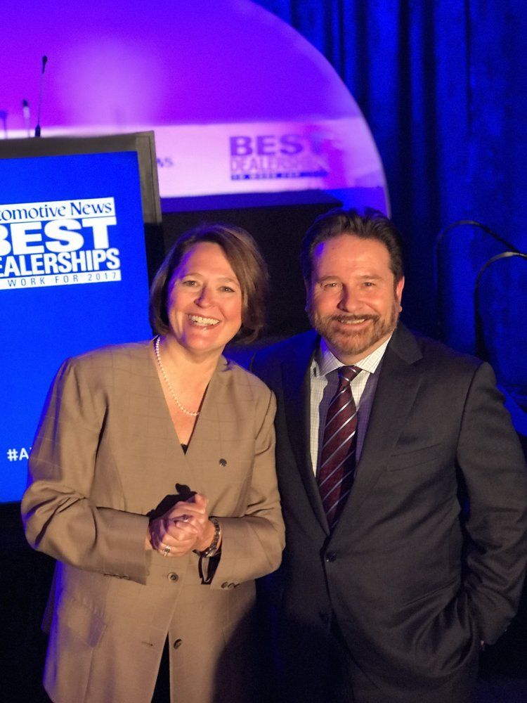 A man and a woman standing in front of a screen that says best dealerships