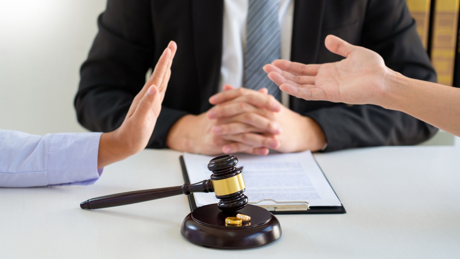Business meeting with gavel and folder as two people gesture across a table
