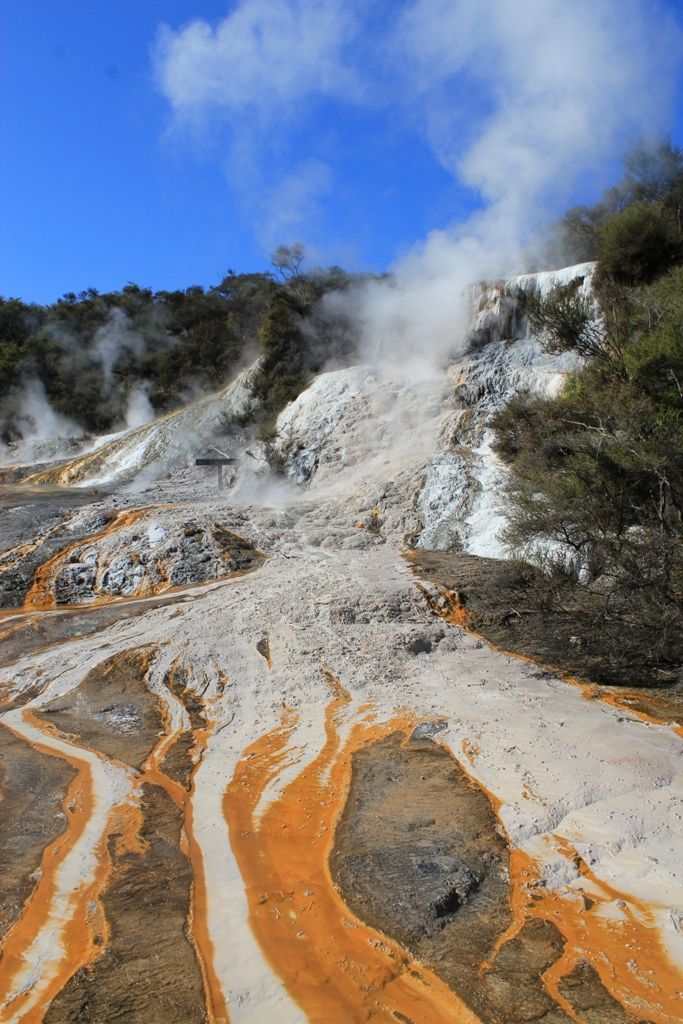 A volcano with steam coming out of it and trees in the background.
