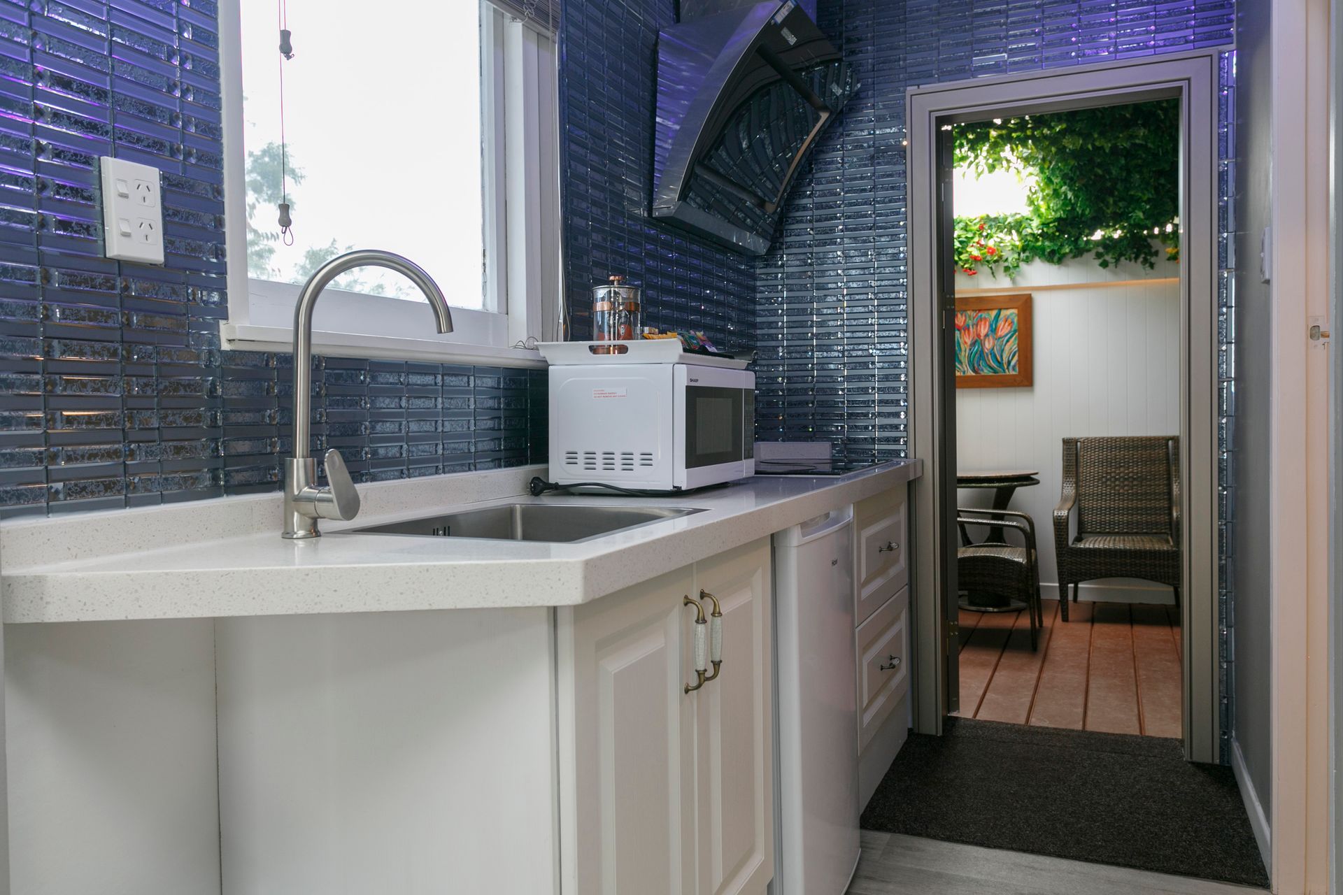 A kitchen with a sink , microwave , and a window.