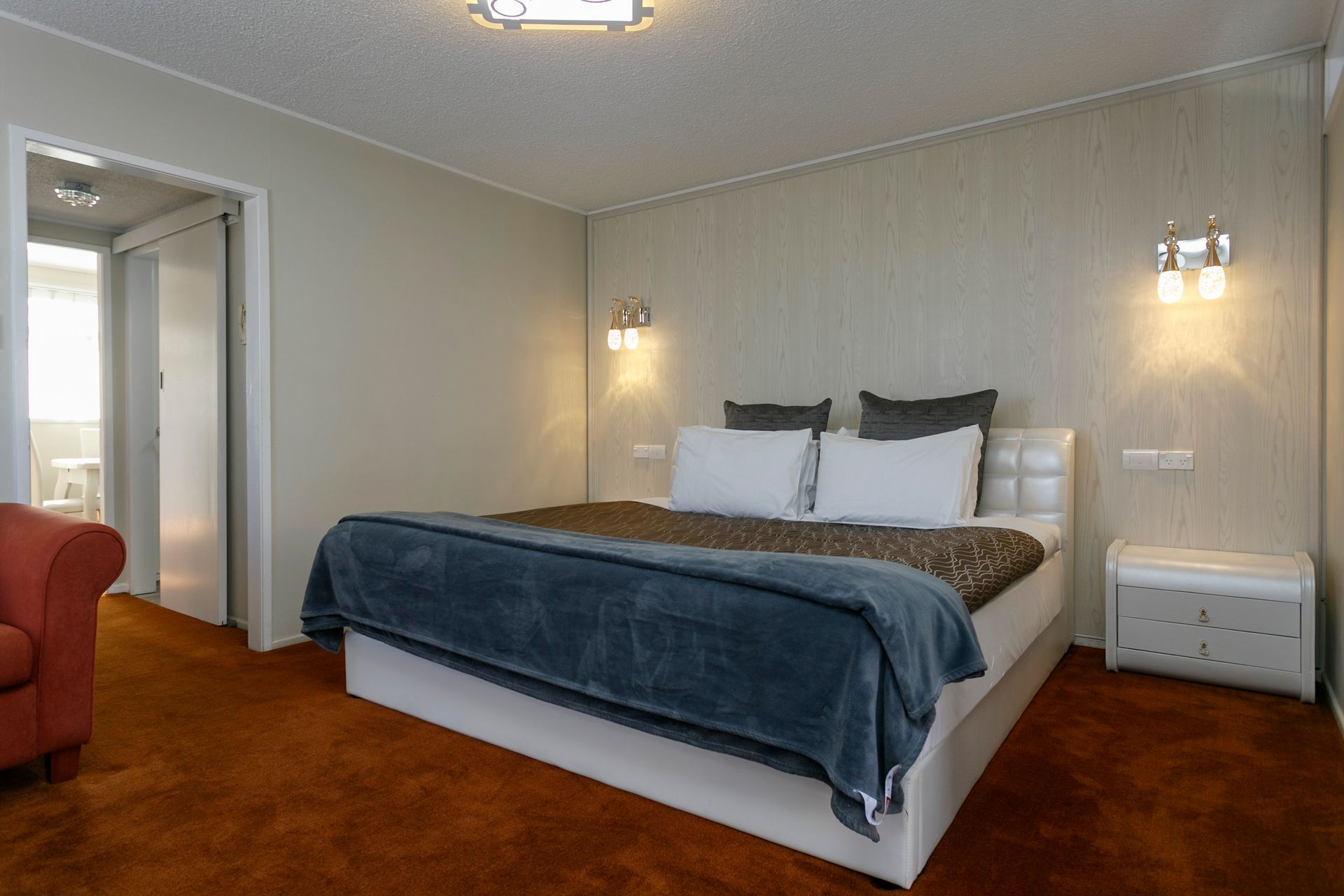 A hotel room with a large bed and a chair