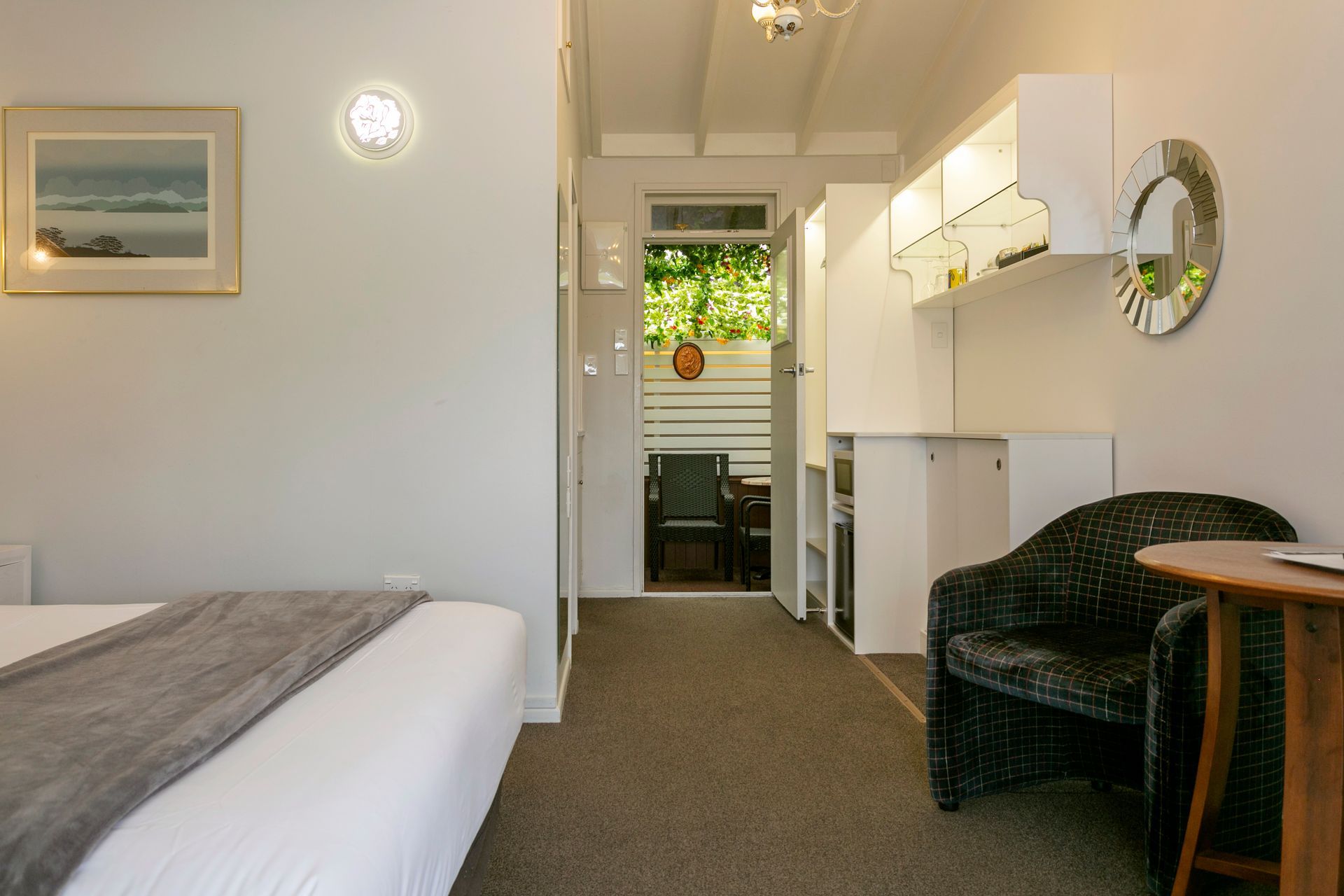 A bedroom with a bed , chair , table and mirror.